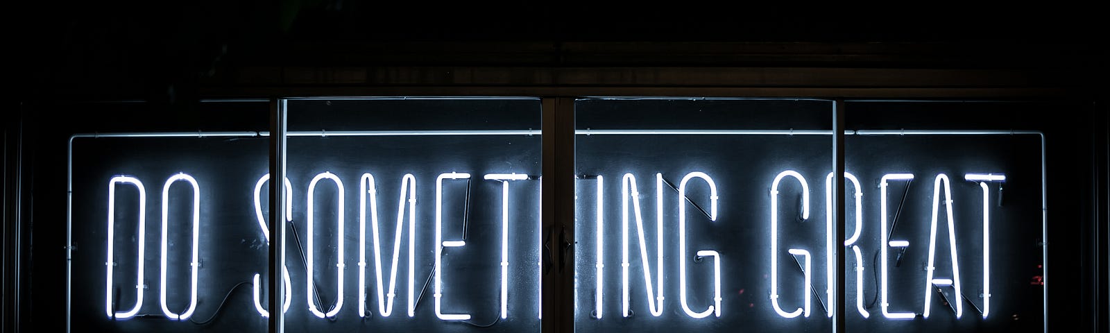 Black background featuring a white neon sign with the words: Do Something Great