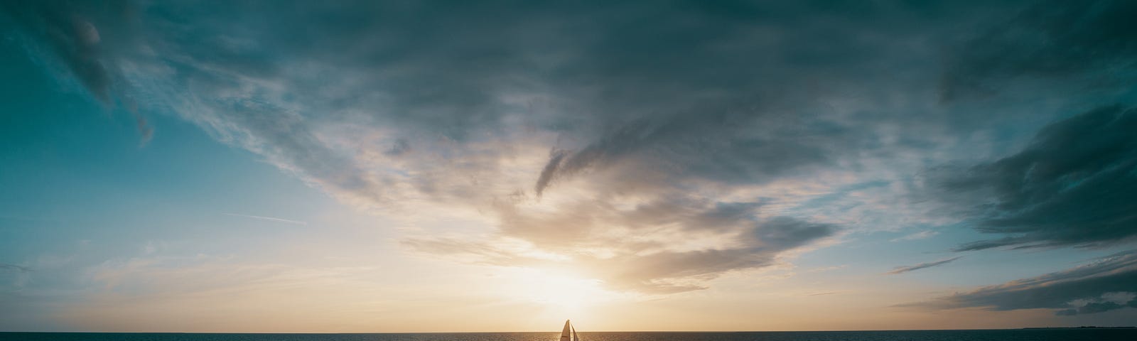 A sailboat in the ocean at the sunset.