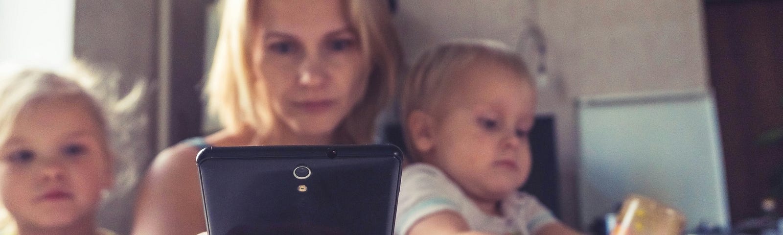 woman with two children, checking phone at the dinner table