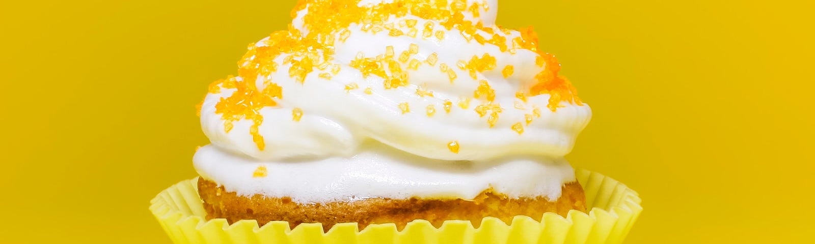 yello cupcake with white cream and yellow sprinkles. Yellow background