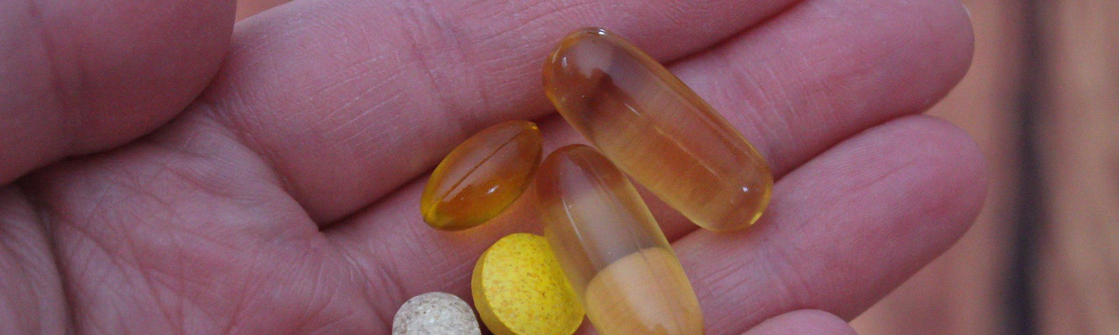 A hand holding assorted vitamin pills.