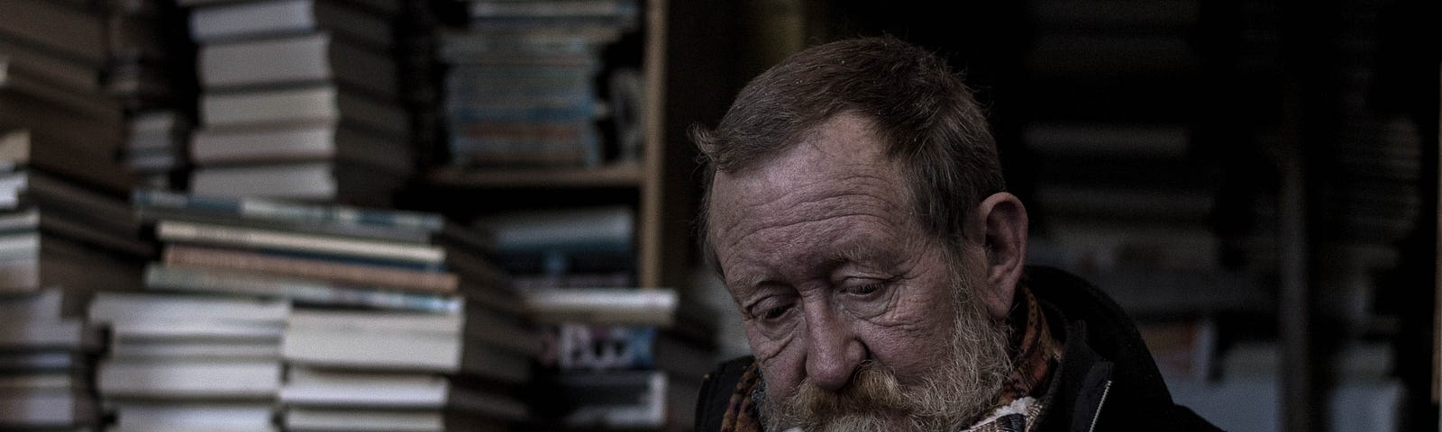 Old man reading next stacks of books