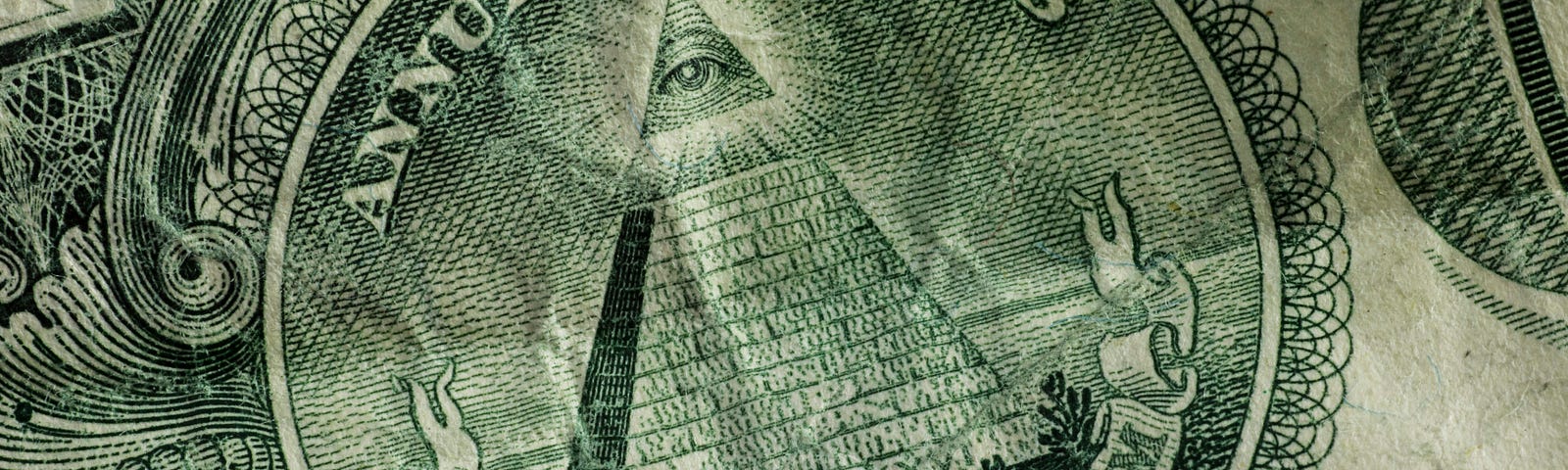 A close-up of a dollar bill, showing the great seal with the ‘illuminatus’ eye