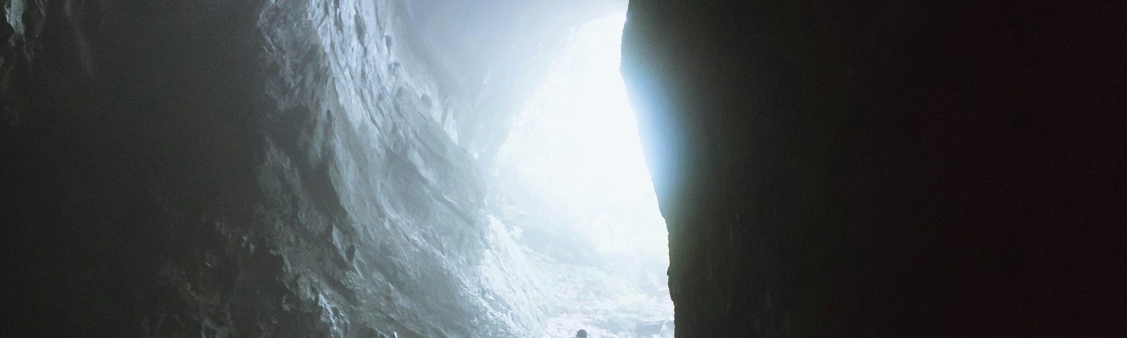 Massive cave with a person scrambling over rocks