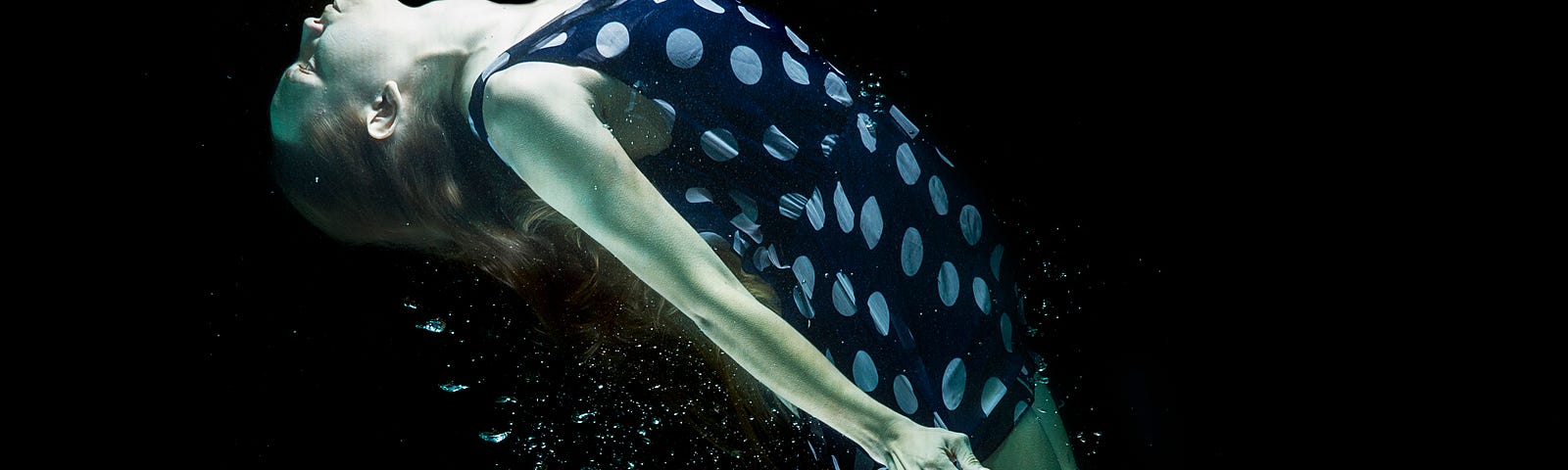 A woman dressed in a blue poker doted dress is seen levitating.