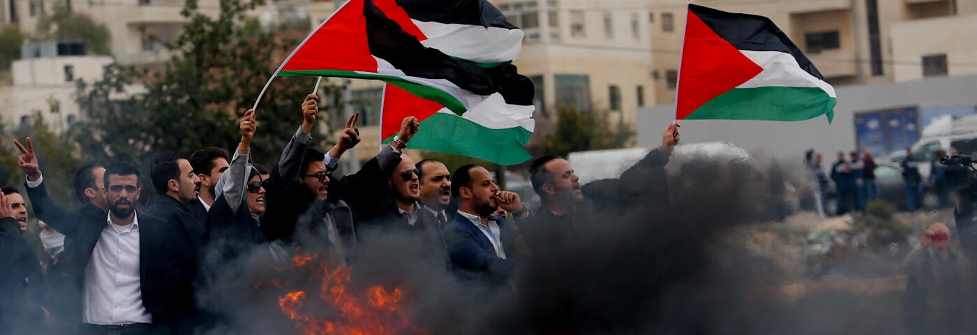 Un grupo de abogados palestinos sostiene banderas nacionales durante una protesta contra la decisión del presidente estadounidense Donald Trump de reconocer a Jerusalén como la capital de Israel, en la ciudad de Ramala, en Cisjordania, el 13 de diciembre de 2017. (Foto: Naser Shiyuji / AP)