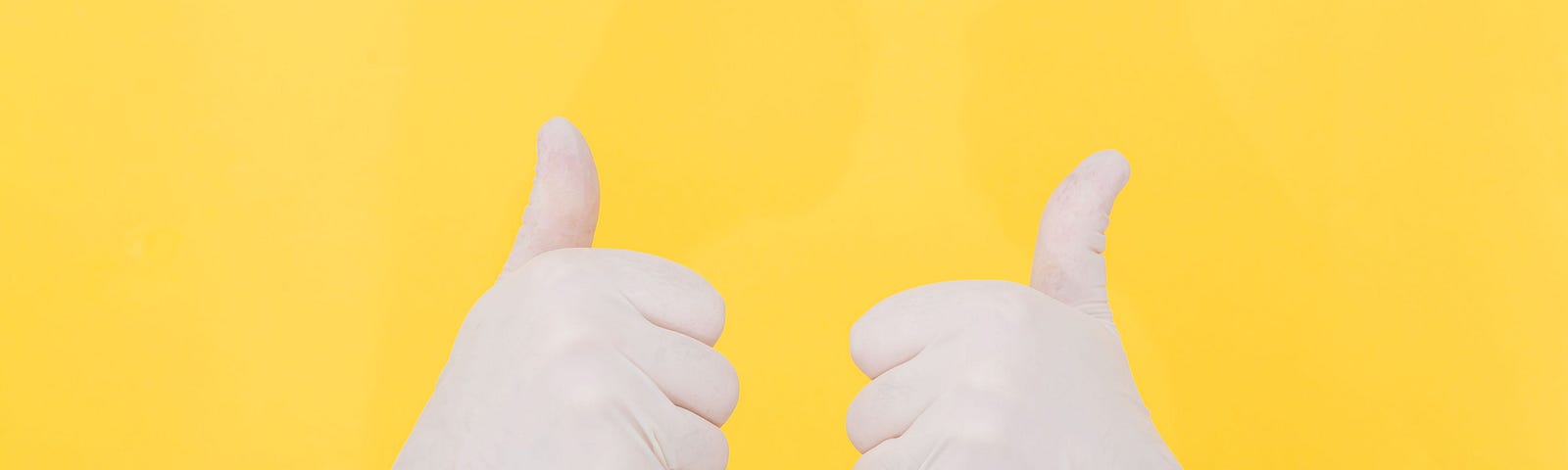 Image of two gloved hands in a “thumbs up” on a yellow background