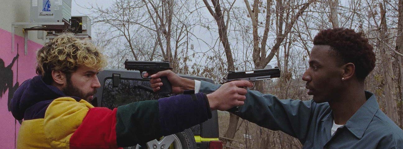 Christopher Abbott and Jerrod Carmichael holding guns