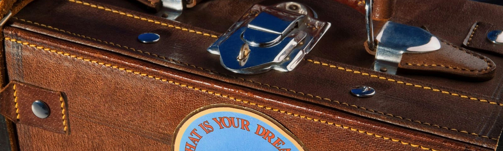 brown leather suitcase with travel stickers on the bottom