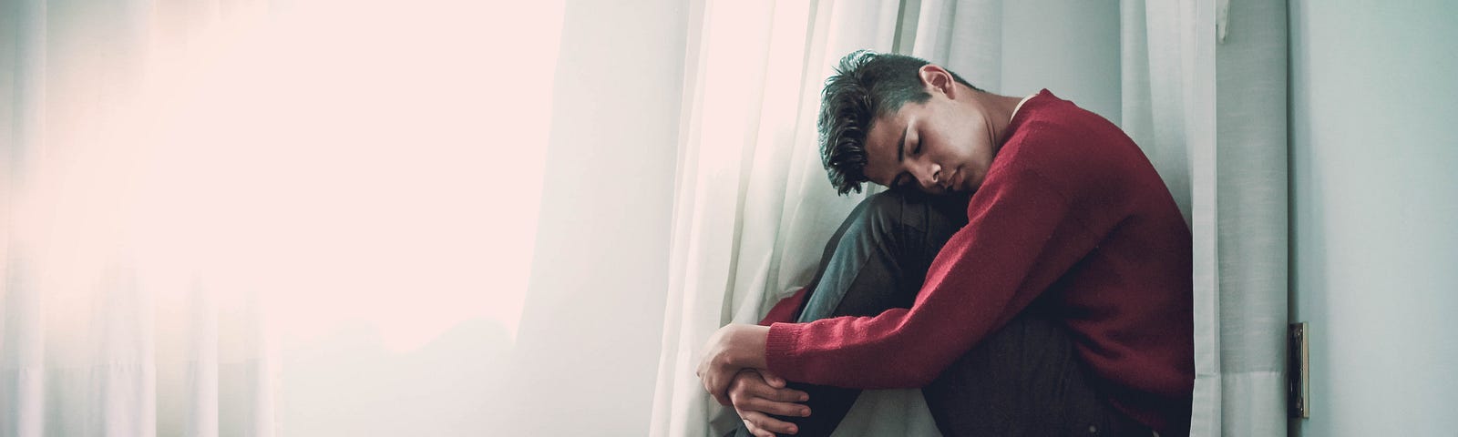 young man hunched on the floor feeling depressed.