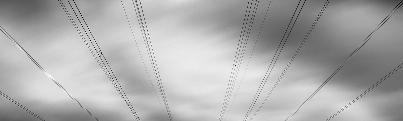 Two sets of power lines against a gray sky.