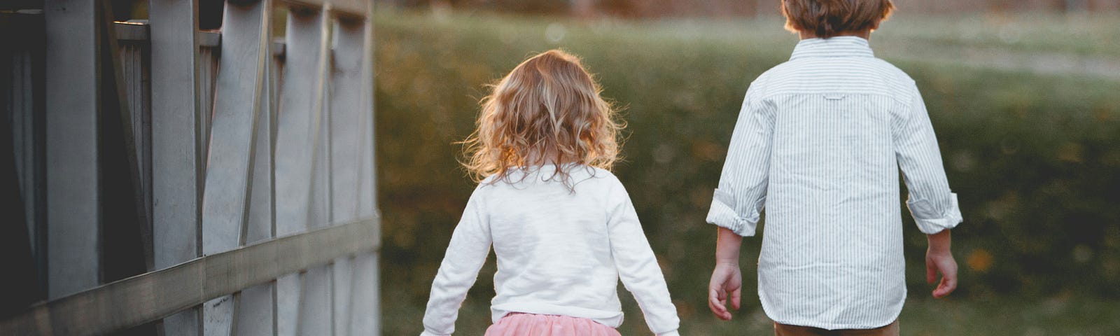 girl and boy walking across a leaf-strewn bridge