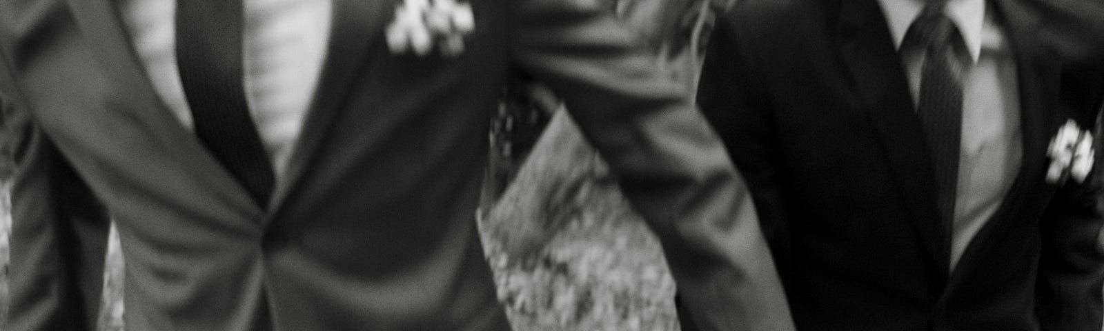 Two men in suits, running together, holding hands.