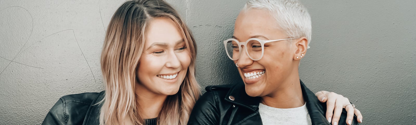 A black and a white lady exchanging smiles and a hug