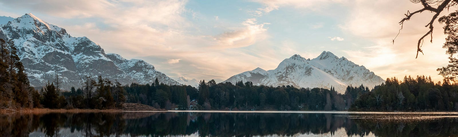 Argentina crystal blue water with snow covered mountain range in backdrop.