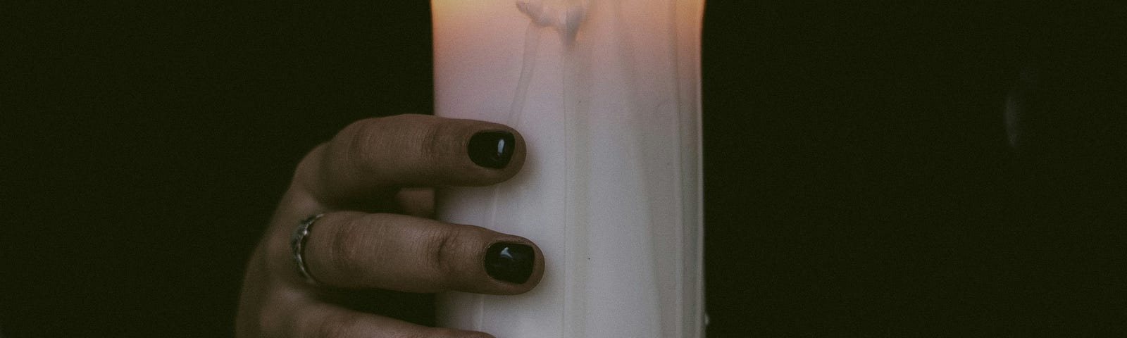 A broad candle clasped in the hands