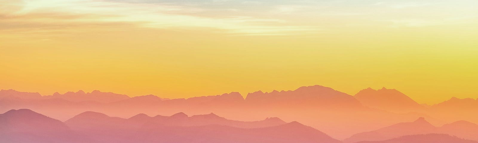 an alluring landscape of dusky mountains with a person standing, pinkish-yellow horizon and white/blue skies.