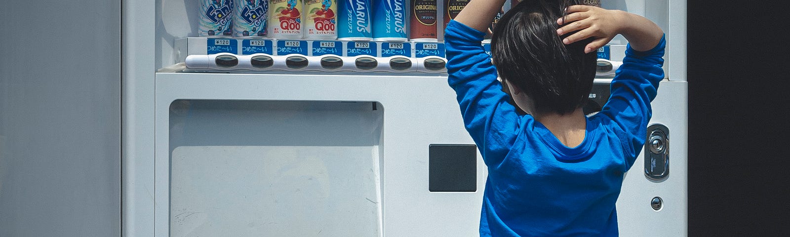In this photo, we have a boy in front of a vending machine, trying to figure out what soft drink to choose.