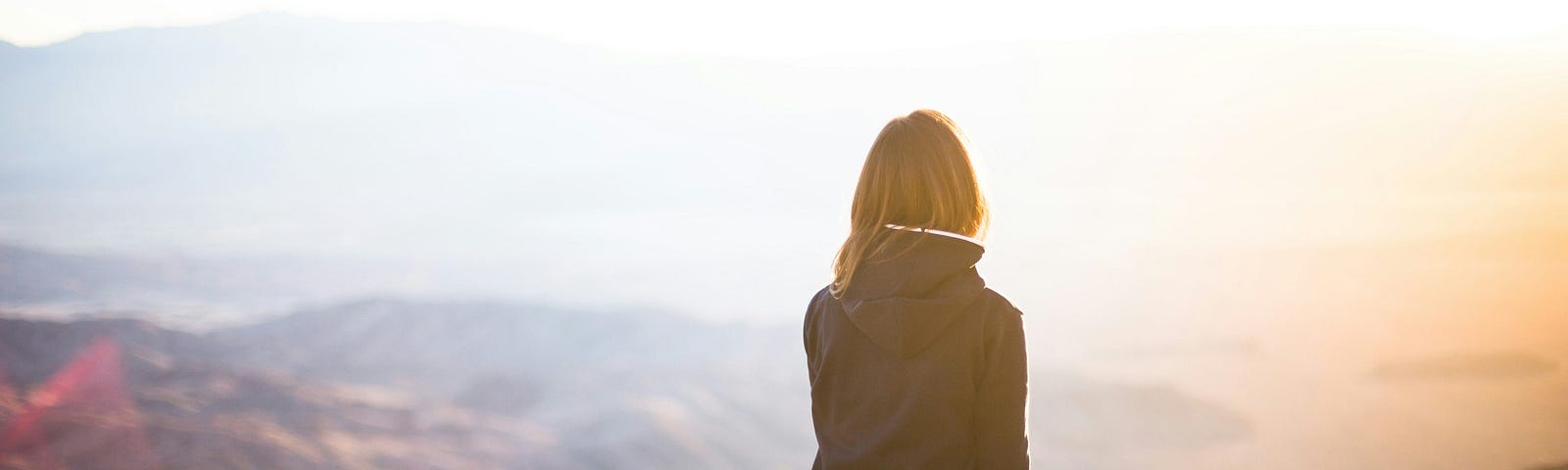 Woman sitting on top of a mountain, looking at the view