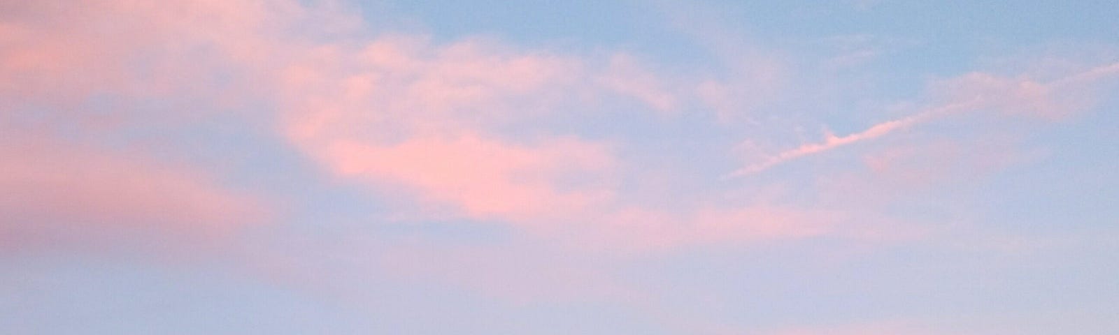 A sky is shown with very faint wisps of pinkish clouds with blue behind them.