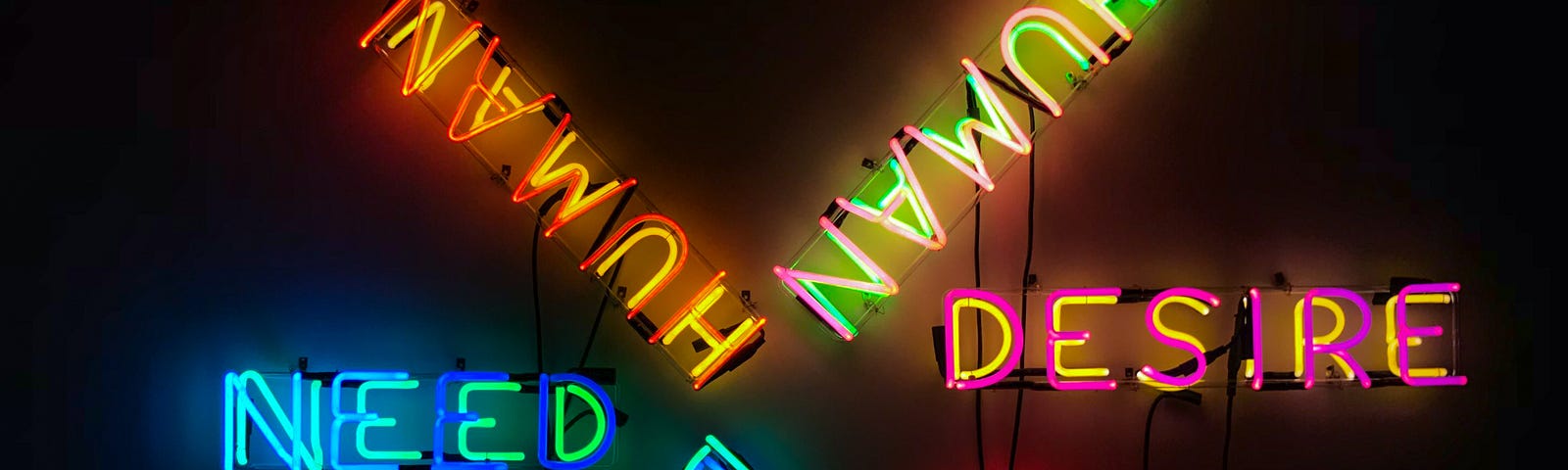 A colourful neon display forms a star pattern against a black background, featuring the words: Need, Human, Desire and Hope.