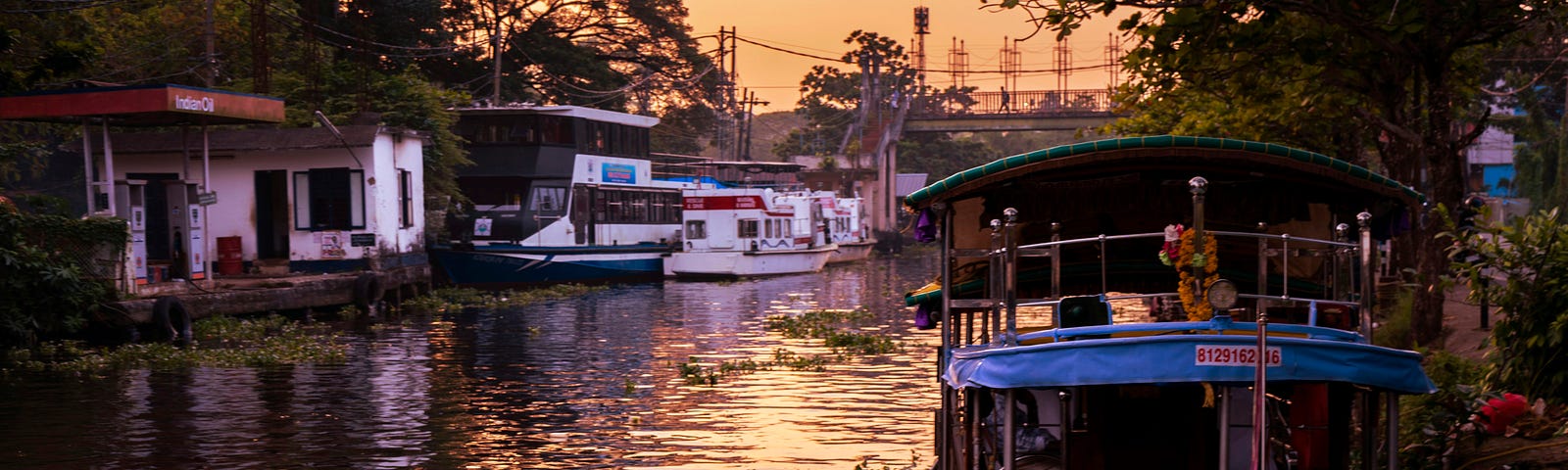 weathered Boats anchored on the banks of a river in India at sunset. a blue one in the foreground.