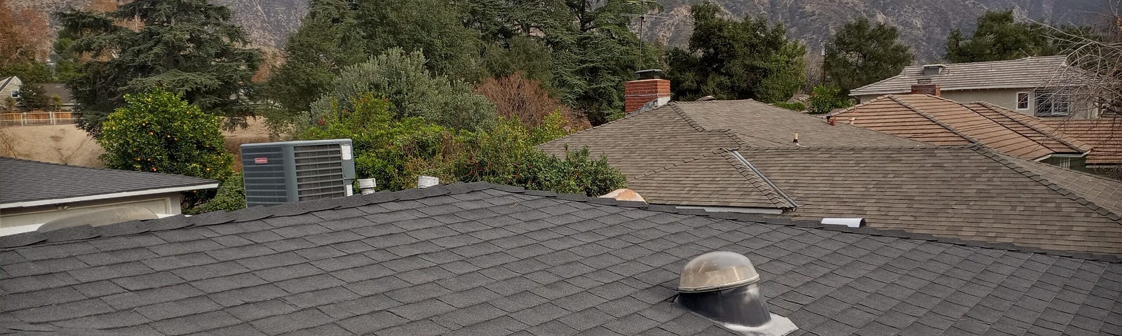 Tops of residential roofs with hills in background