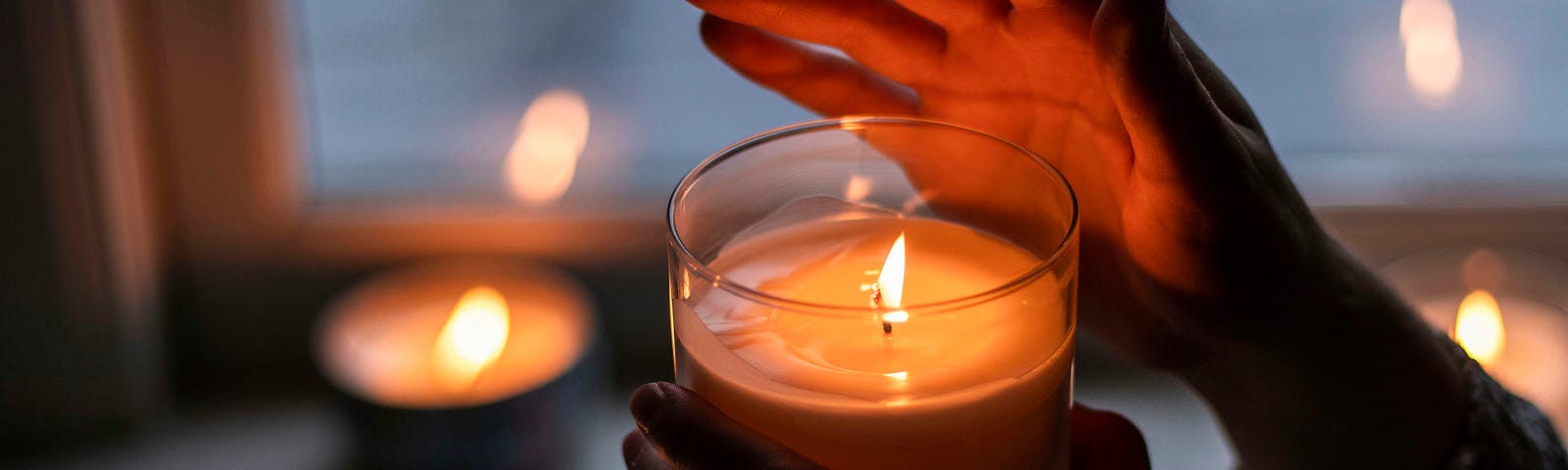 hands holding a lit candle