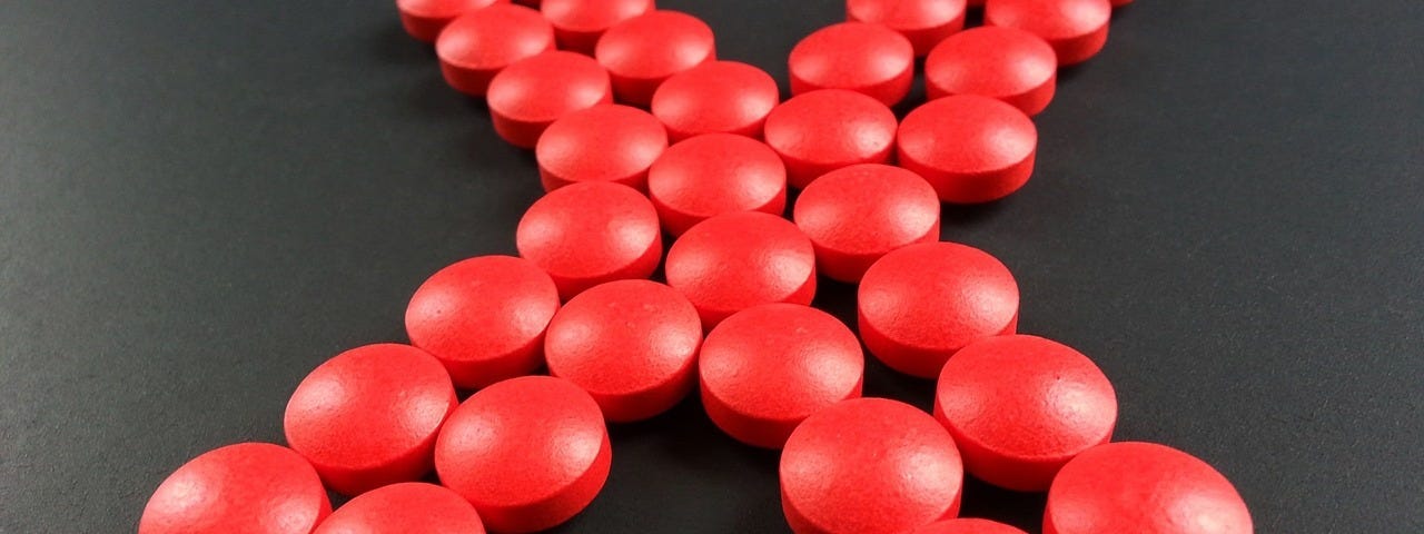 Giant “X” shape made of 32 bright red, round pills.