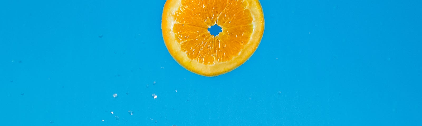 Cut slices of orange, some floating against a blue background. Increasing fruits and vegetables is one of the natural ways that you may drop your blood pressure.