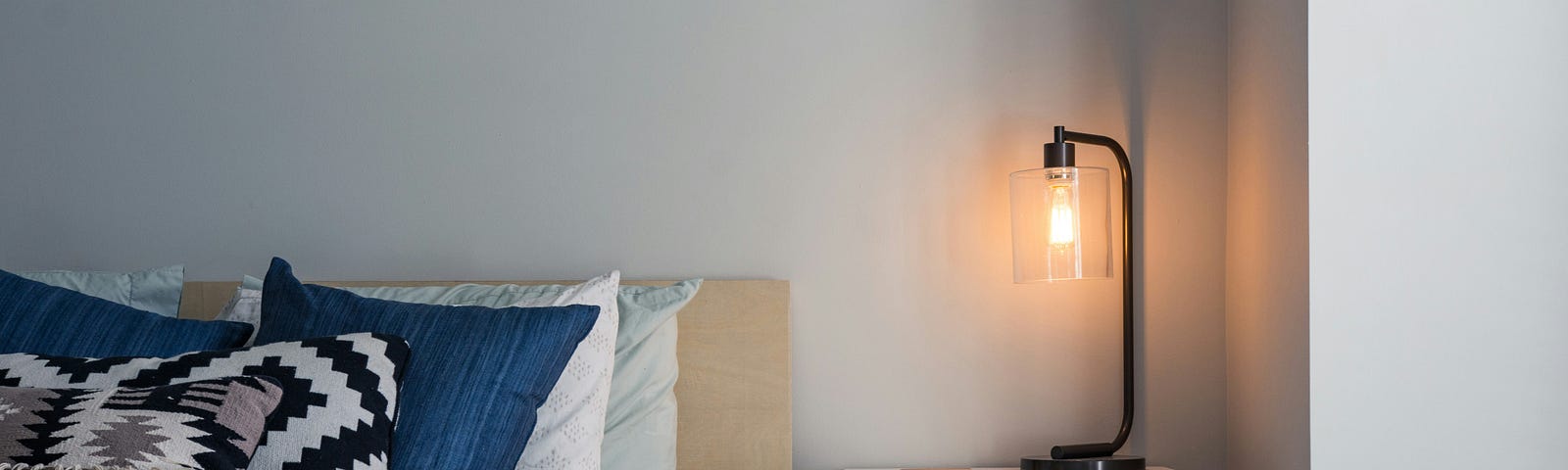 A bed with a white cover and multiple pillows is flanked by a nightstand.