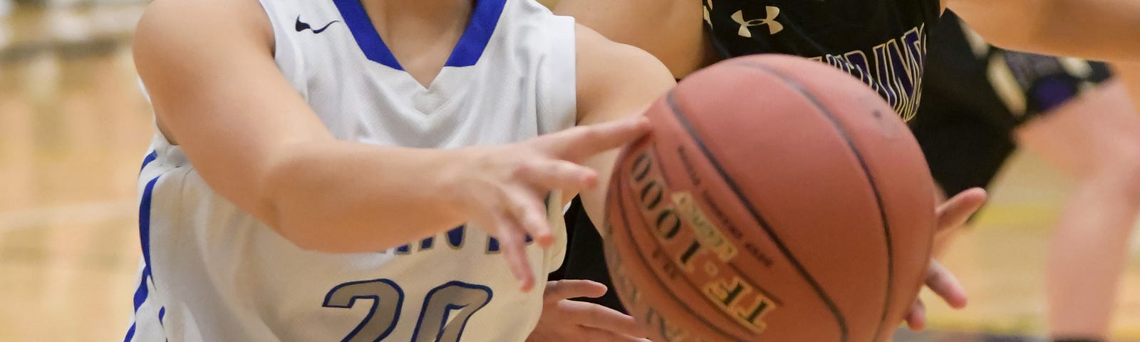 Two girls playing basketball from opposing teams