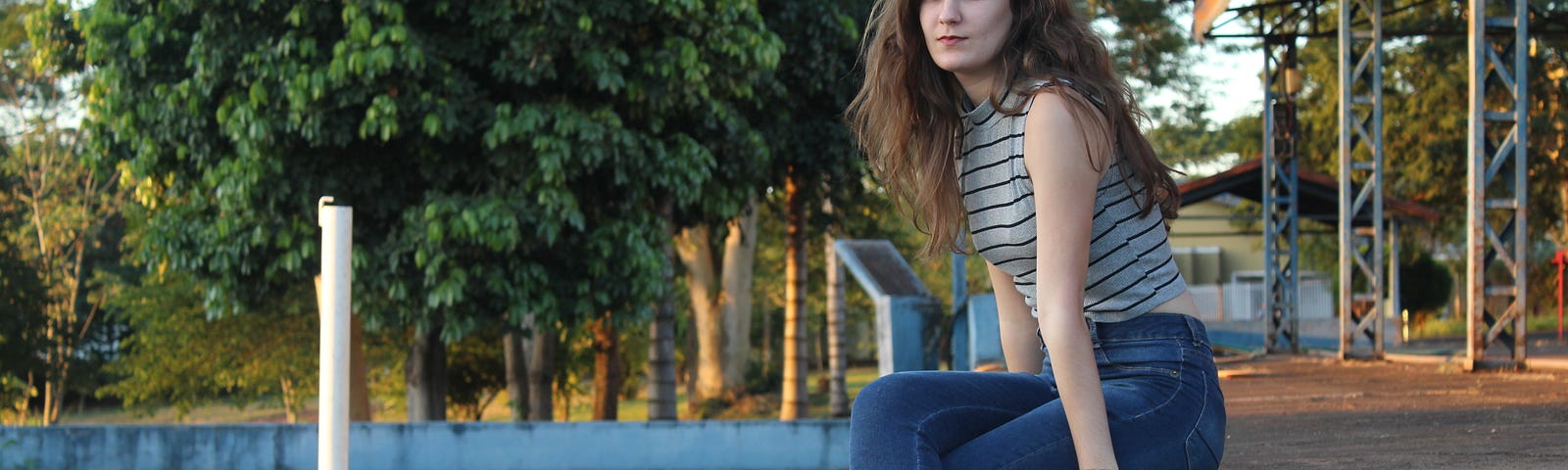 A young woman sitting on a concrete wall.