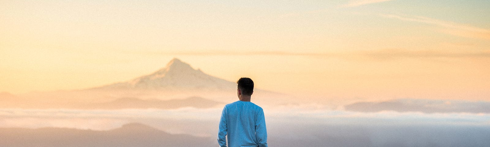 pic of young man enjoying the view of distant mountains and a valley