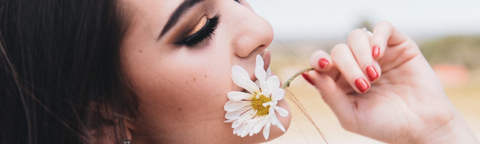 beautiful woman with a daisy brought to her face