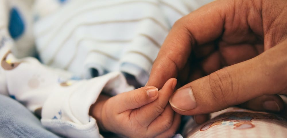 A person holding baby’s index finger