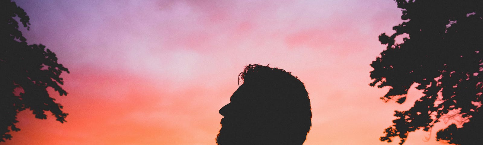 Silhouette of man in wooded area during sunrise.