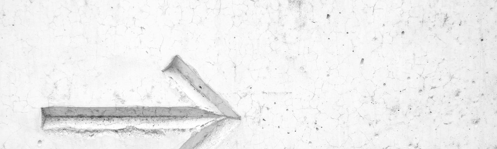 An indented arrow pointing right on a grey concrete background. It looks a bit like Common Collective’s logo.