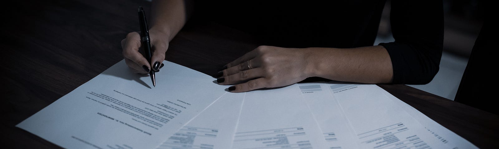 A woman signing a contract with a ballpoint pen