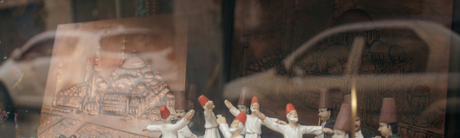 A set of Sufi dancer figurines whirl inside a shop window…