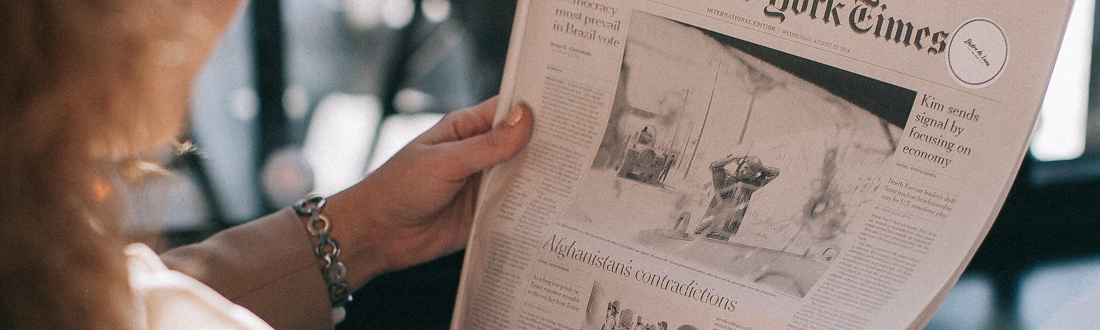 A woman is reading newspaper.