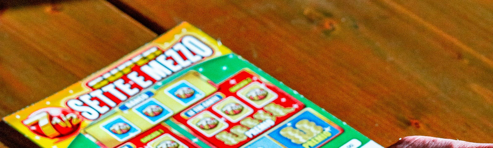 Hand touching jackpot tickets on a wooden surface.