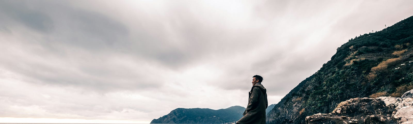 man standing on rock and overlooking water