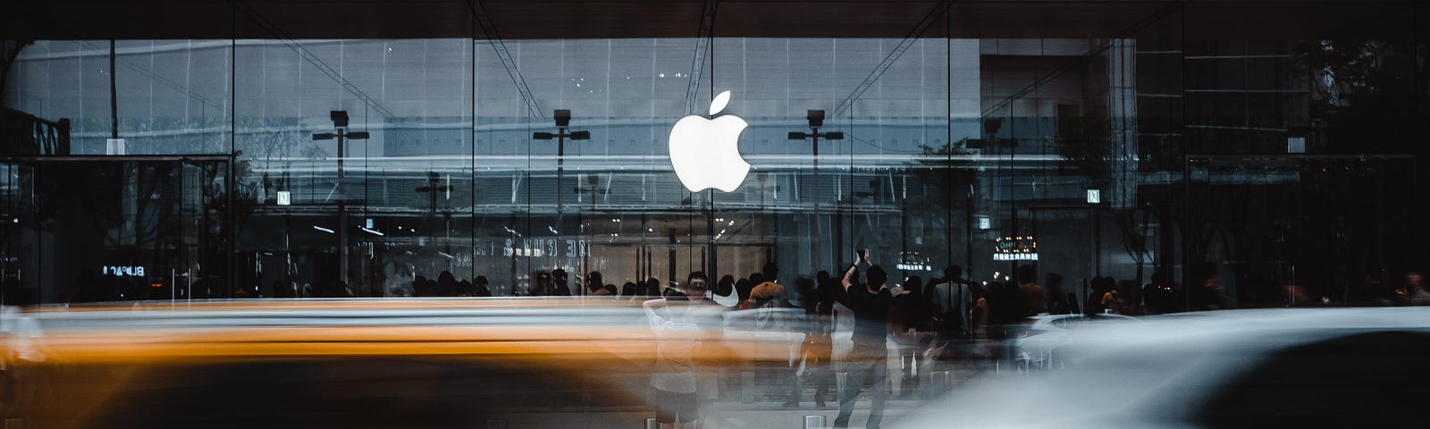 A long exposure image of an Apple store with cars visible in the foreground