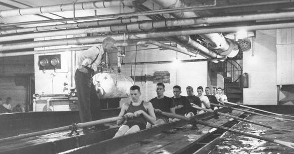 image from old newspaper with crew cut crew rowers in a shallow pool in what looks like a basement