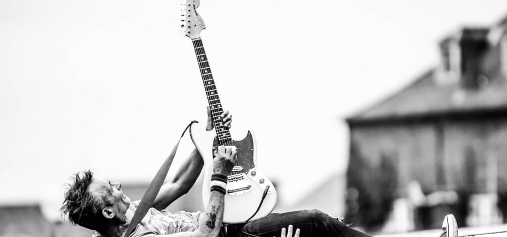 Profile of a guitar player crowd surfing on his back while playing. Photo courtesy of Thibault Trillet at Pexels