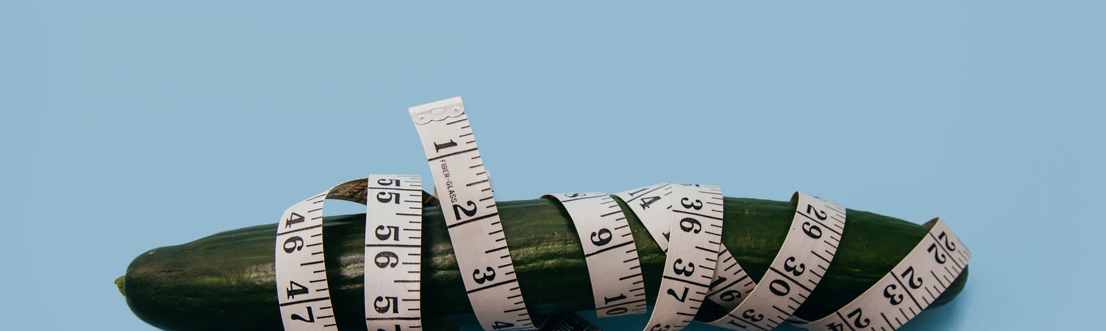 Photo of a sad-looking, wilty cucumber wrapped in a tape measure