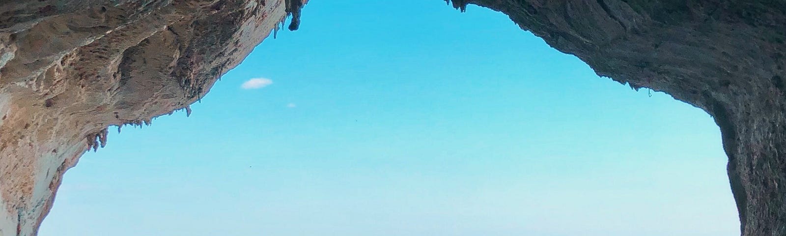 Looking out from a cave, we see several people on a bright sunny day. There is an aquamarine ocean in the background. Blue Zones are regions of the world where people live longer and healthier lives compared to the global average. The term “Blue Zones” was coined by Dan Buettner, a National Geographic explorer, who identified five areas with high concentrations of centenarians (people who live to be 100 or older).