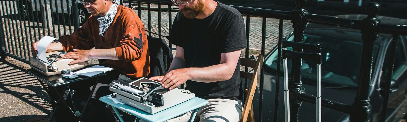 Men writing on typewriters outdoors