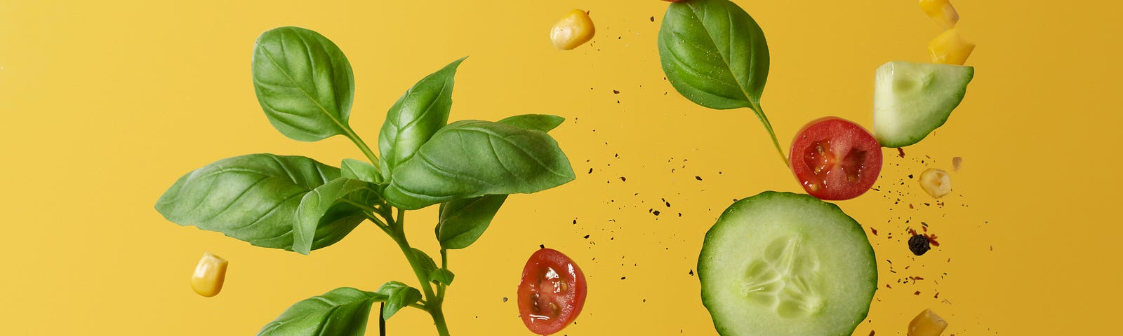 Photograph of avocado, tomatoes, and herbs falling on a yellow background. Healthy eating. Weight loss